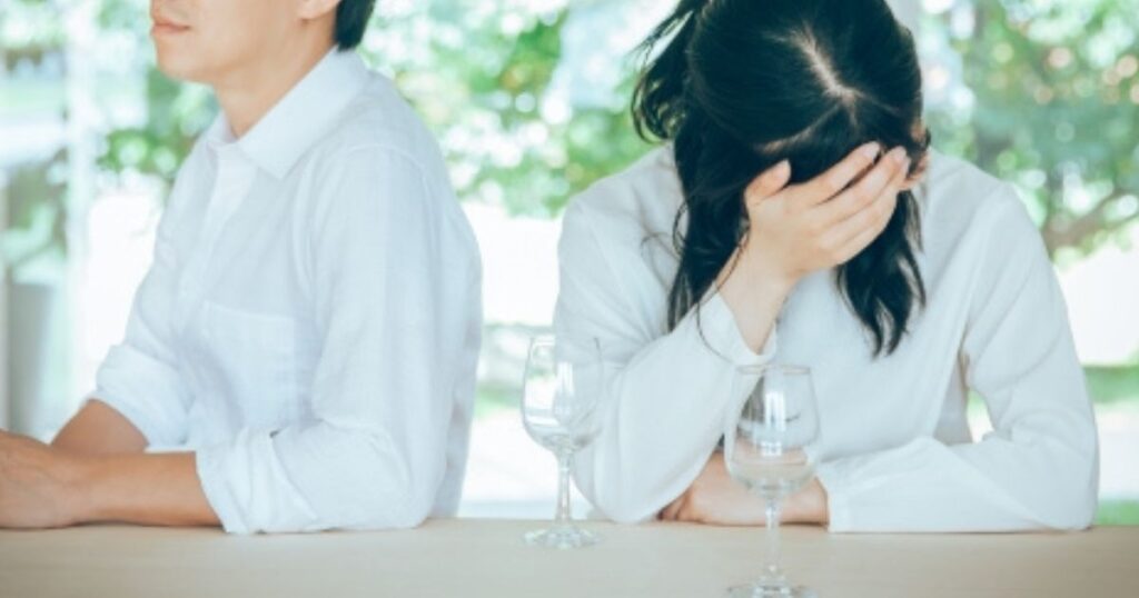 悩んで頭を抱える妻と背を向ける夫