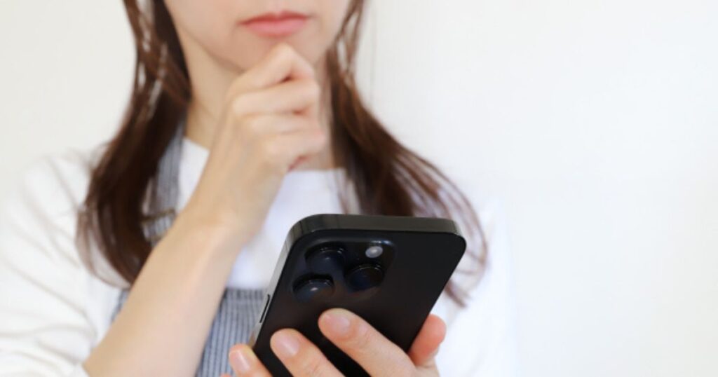 スマホを見て考え込む妻