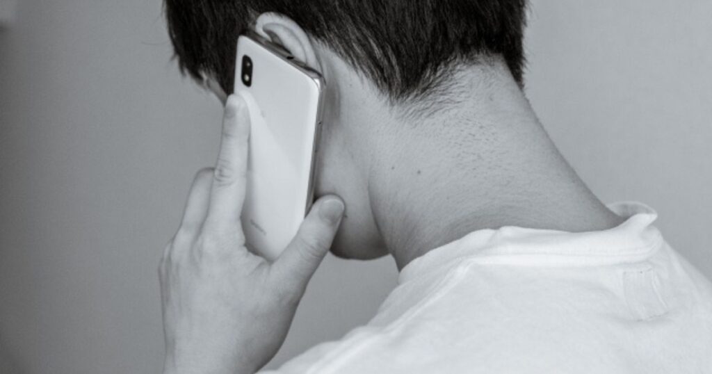 背を向けて誰かに電話をする夫