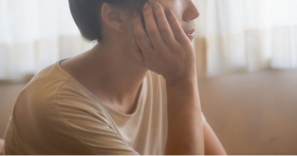 考えながら頬に手を当てて遠くを見つめる女性