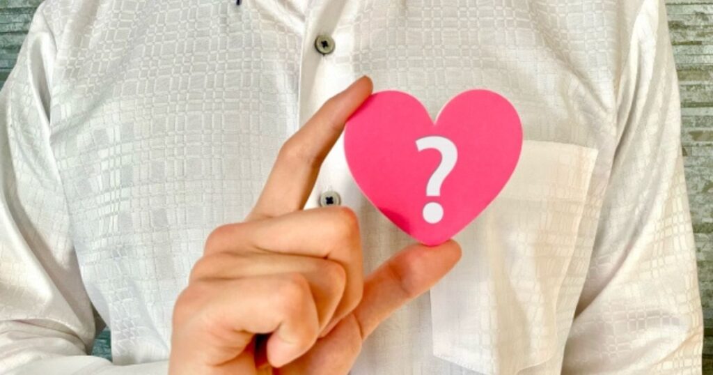 左胸にクエッションマークのついたハートを添える男性